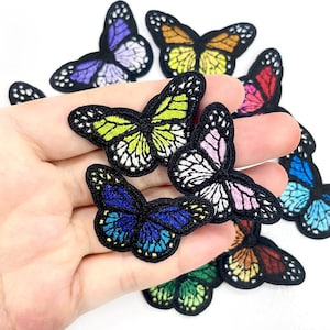 May include: A selection of embroidered butterfly patches in various colours. The patches feature detailed wing patterns and black borders. Colours include blue, green, yellow, pink, and orange. Ideal for crafts and embellishments.
