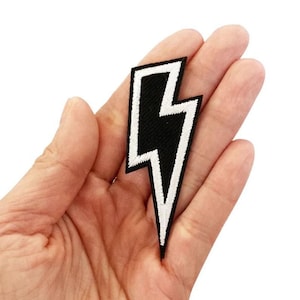 May include: Black and white embroidered lightning bolt patch. The patch has a white outline and a black interior.