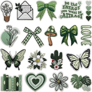 Può includere: Una collezione di toppe ricamate verdi e bianche con vari disegni. Sono inclusi farfalle, fiocchi, fiori, un fungo, un cactus e il testo "be the ENERGY you want to ATTRACT".