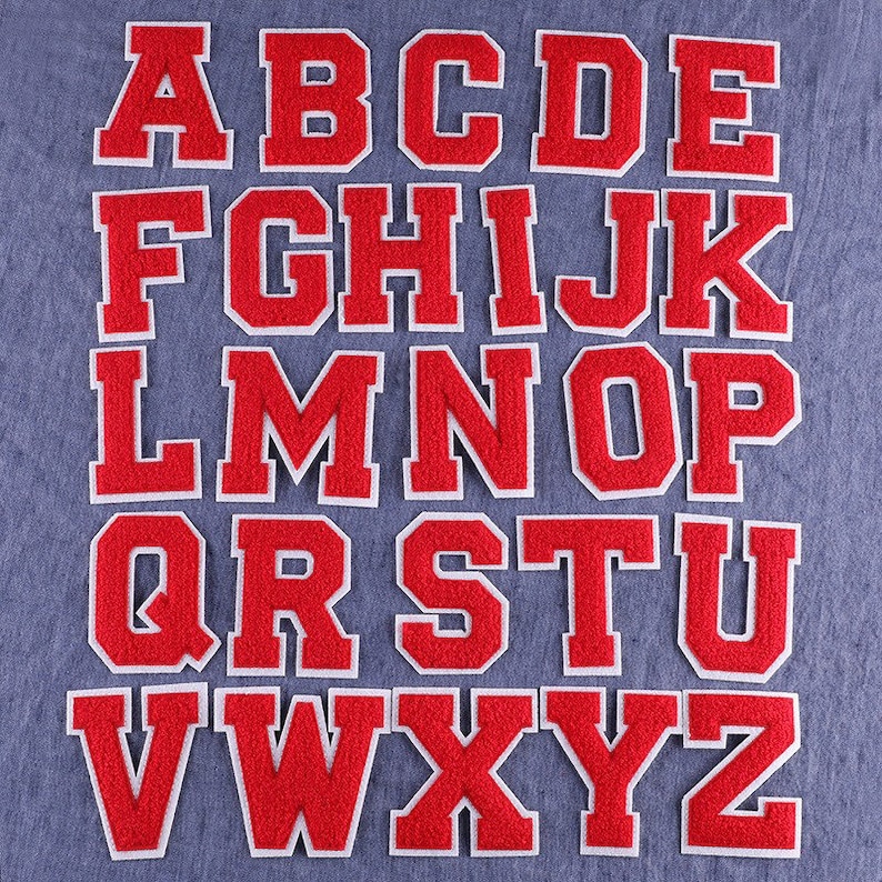 Op de afbeelding: Een set van 26 rode viltletters met witte contouren, die het Engelse alfabet voorstellen. De letters zijn alfabetisch gerangschikt en zijn perfect voor knutselprojecten.