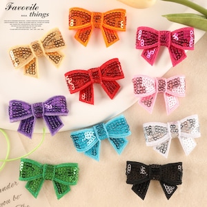 May include: Assortment of ten colorful sequined bows in various colors including gold, orange, pink, red, purple, blue, white, green, and black.  The bows are arranged on a white surface with the text "Favorite things" at the top of the image.