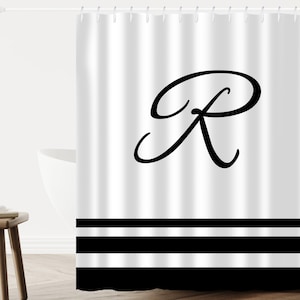 May include: White shower curtain with a black cursive letter R in the center and three black horizontal stripes at the bottom.