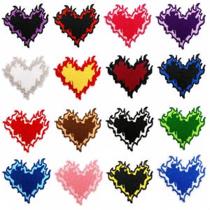 Puede incluir: Una colección de parches bordados con forma de corazón en varios colores, incluyendo morado, rojo, amarillo y verde. Cada corazón presenta un borde en forma de llama, creando un diseño único. Estos parches son adecuados para ropa o accesorios.