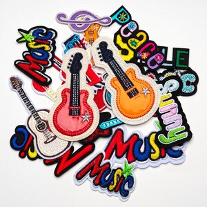 May include: A selection of colourful embroidered patches with musical themes. The patches feature guitars, musical notes, and the word "Music" in various fonts and colours. Some patches have a star design.