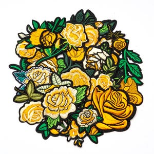May include: A collection of embroidered rose patches in various sizes and stages of bloom. The patches feature yellow and white petals with green leaves and stems, all outlined in black.