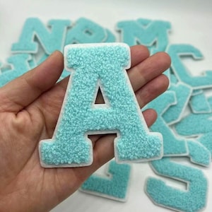 May include: A light blue felt letter A with a white outline. The letter is part of a set of felt letters.