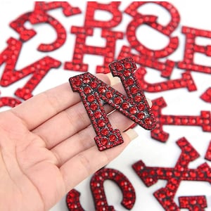 Op de afbeelding: Rode strass letter N, onderdeel van een set alfabetletters bedekt met rode strass steentjes.