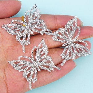Peut inclure: Trois embellissements en strass en forme de papillon argentés. Chaque papillon est composé de petits strass scintillants.
