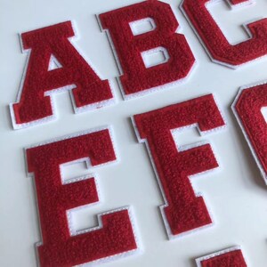Op de afbeelding: Rode vilt letter patches met witte randen. De letters zijn A, B, C, E en F.