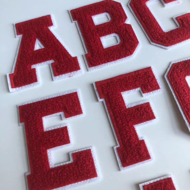 Op de afbeelding: Rode vilt letter patches met witte randen. De letters zijn A, B, C, E en F.