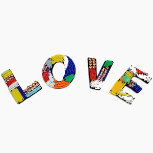 May include: The word "LOVE" spelled out in colorful beaded letters. Each letter is made of a variety of colors, including red, blue, yellow, green, and white.