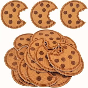 May include: A set of 10 brown and white cookie iron-on patches. Each patch is shaped like a bitten cookie with chocolate chips.