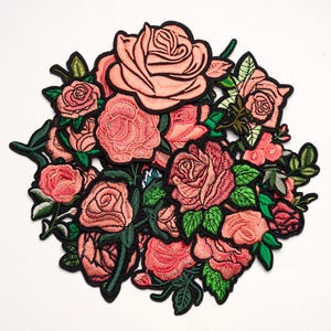May include: A collection of embroidered rose patches featuring various shades of pink and peach petals with vibrant green leaves. Each individual rose motif is outlined in a bold black border, creating a dense, layered floral arrangement.