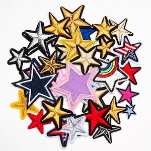 Puede incluir: Una colección de parches bordados en forma de estrella en varios colores, incluyendo dorado, plateado, rojo, azul y rosa. Algunos parches presentan diseños patrióticos, mientras que otros tienen acentos de arcoíris o purpurina. Estos parches son ideales para decorar ropa o accesorios.