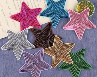 May include: Assortment of eight star-shaped iron-on patches in various colors, including pink, blue, green, brown, gray, and purple. The patches are made of sequins and have a shiny finish.