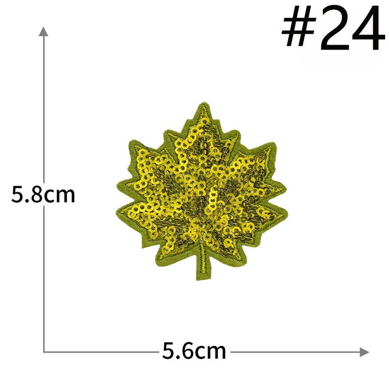 Pu&ograve; includere: Una toppa a forma di foglia d'acero con paillettes gialle su una base in tessuto verde. La toppa &egrave; contrassegnata con #24 e misura 5,8 cm in altezza e 5,6 cm in larghezza, come indicato dalle linee di misurazione e dal testo visibili.
