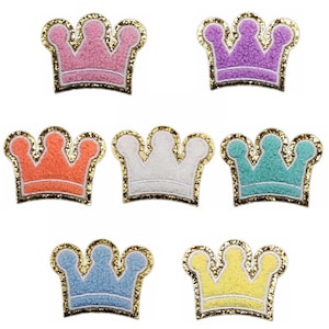 May include: Six felt crowns with gold glitter trim. The crowns are in pink, purple, orange, white, light blue, and yellow.