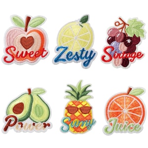 Op de afbeelding: Een set van zes geborduurde fruitpatches met een appel met de tekst Sweet, een citroenschijfje met Zesty, druiven met Vintage, avocado's met Power, een ananas met een zonnebril en Sunny, en een sinaasappelschijfje met de tekst Juice.