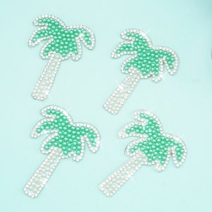Puede incluir: Cuatro parches de planchado en forma de palmera verde y blanca con pedrería. Las palmeras están hechas de pequeñas cuentas verdes y blancas.