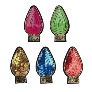 May include: Six colorful light bulb shaped patches with sequins. The patches are in red, green, gold, blue, and pink.