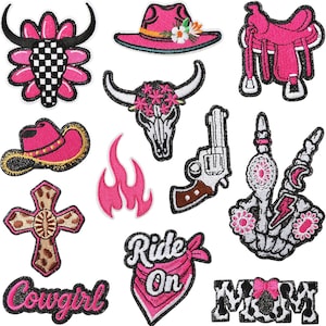 Peut inclure: Collection d'écussons brodés sur le thème du western. Les motifs comprennent un crâne de taureau, des chapeaux de cow-boy, une selle, un revolver, une croix, des flammes et les mots "Cowgirl", "Ride On" et "MOM". Les écussons sont principalement roses, noirs, blancs et bruns.