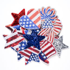 May include: A collection of patriotic sequin embellishments in red, white, and blue. The assortment includes stars, hearts, bows, and a top hat, all adorned with shimmering sequins. Perfect for crafting and adding a festive touch to any project.