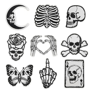 Può includere: Set di 10 toppe termoadesive in bianco e nero con vari disegni di teschi, tra cui un teschio con una rosa, un teschio con ossa incrociate, un teschio con un cuore, un teschio con una luna crescente, un teschio con una farfalla, un teschio con una carta da gioco e una mano scheletrica che forma un cuore.