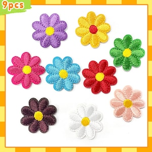 May include: Nine colorful daisy flower patches in various colors, including purple, yellow, green, pink, blue, red, brown, white, and light pink. Each patch has a yellow center and a stitched border. The top left corner has the text "9pcs".