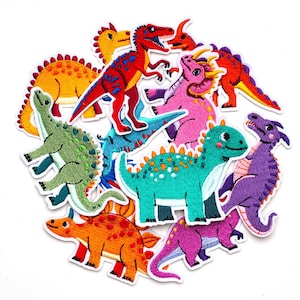 Op de afbeelding: Een verzameling kleurrijke dinosauruspatches in verschillende vormen en maten. De patches hebben geborduurde details in tinten rood, oranje, groen, blauw, roze en paars. Elke patch heeft een witte rand.