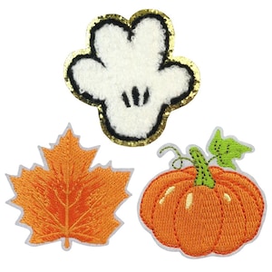 May include: Three embroidered iron-on patches: a white hand with black details, an orange maple leaf, and an orange pumpkin with a green stem.
