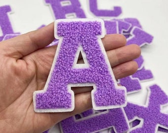 May include: Purple felt letter patches with white outlines. The letters are A, B, C, D, E, F, G, H, I, J, K, L, M, N, O, P, Q, R, S, T, U, V, W, X, Y, and Z.