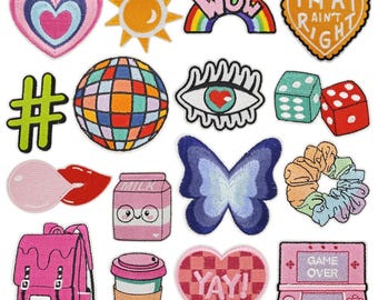 May include: A collection of embroidered patches in various shapes and colors. Designs include a heart, sun, rainbow, eye, dice, butterfly, backpack, coffee cup, and a retro video game console. Some patches have text like "WOW" and "YAY!"