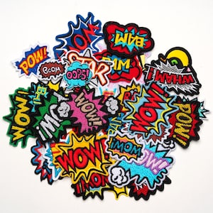 Peut inclure: Un assortiment de patchs de style bande dessinée avec des exclamations telles que "WOW!", "POW!" et "BAM!" dans des polices audacieuses et stylisées. Les patchs présentent des couleurs vives, notamment le rouge, le jaune, le bleu et le vert, avec des contours noirs.