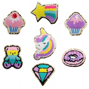 May include: Set of seven colorful iron-on patches featuring a unicorn, a star, a donut, a cupcake, a diamond, a teddy bear, and a cupcake. The patches are made of fluffy fabric and have a gold glitter outline.