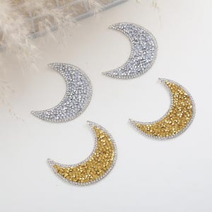 May include: Four crescent moon shaped embellishments, two silver and two gold, made of rhinestones.
