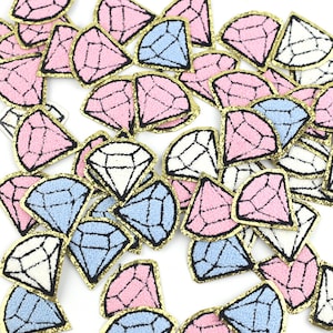 May include: A collection of colourful diamond-shaped fabric patches with gold glitter trim. The patches are in pink, blue, and white.