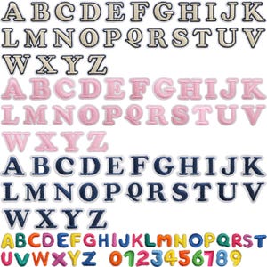 May include: An assortment of embroidered alphabet letters and numbers in different colours. The letters are in beige, pink, and navy blue, with a white border. The numbers are in rainbow colours. These patches are suitable for customising clothing.