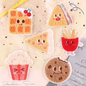 May include: Set of 6 embroidered iron-on patches featuring various food items with cute faces. The patches include a waffle, a sandwich, a pizza slice, french fries, popcorn, and a cookie.
