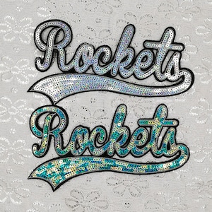 May include: Two sequined patches with the word "Rockets" in a cursive font. The top patch is silver and the bottom patch is teal.