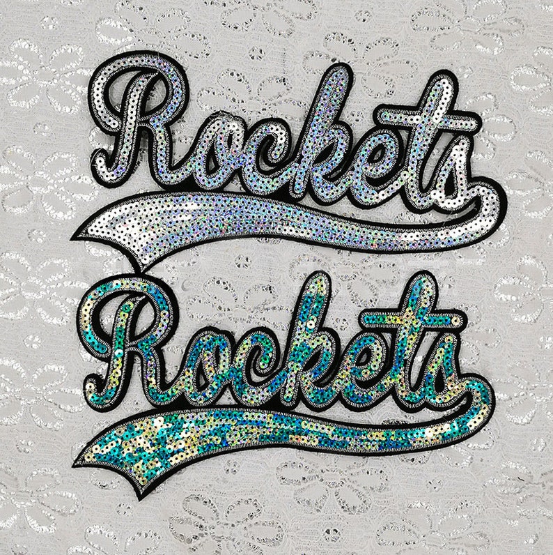 Op de afbeelding: Twee patches met pailletten met het woord "Rockets" in een cursief schrift. De bovenste patch is zilver en de onderste patch is turquoise.