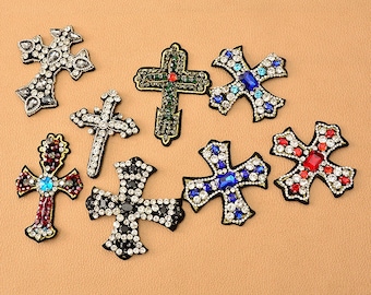 May include: Assortment of nine rhinestone cross patches in various colors, including red, blue, black, and green. The crosses are embellished with sparkling rhinestones.