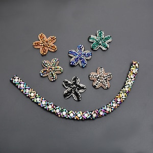 May include: Assortment of six colorful flower-shaped rhinestone embellishments with a single iridescent trim.