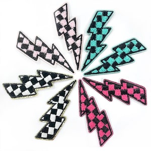 May include: Seven iron-on patches in the shape of lightning bolts. The patches are black and white checkered and have different colored borders: pink, turquoise, and black.