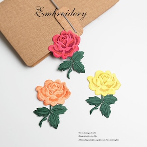 May include: Three embroidered rose patches in pink, orange, and yellow. The roses are detailed with green leaves and stems. The patches are perfect for adding a touch of floral charm to clothing, bags, or other crafts.