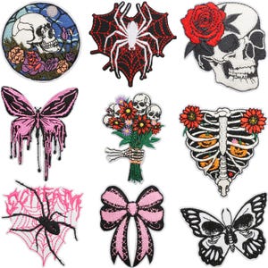 May include: A collection of embroidered patches featuring gothic and Halloween themes. Designs include skulls, spiders, butterflies, a bouquet of skulls, a rib cage, and a bow. The patches are in various colors, including black, white, pink, and red.