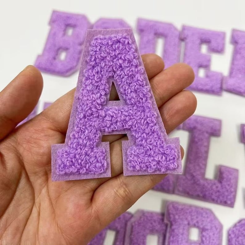 Peut inclure: Lettres en feutre violet en forme de patchs, comprenant les lettres A, B, D, E, I, L et O. Les lettres sont duveteuses et ont un contour blanc.