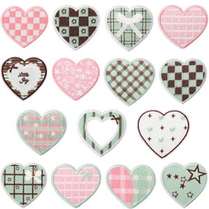 Op de afbeelding: Een verzameling hartvormige patches in verschillende patronen en kleuren. Ontwerpen omvatten ruitjes, ruitjes en bloemmotieven, met accenten zoals strikken en sterren. Sommige patches bevatten de tekst "Little Joy".