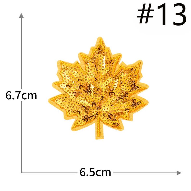 Pu&ograve; includere: Una toppa a forma di foglia d'acero con paillettes dorate etichettata #13. La toppa presenta un bordo ricamato giallo e misura 6,7 cm di altezza e 6,5 cm di larghezza, come indicato dalle linee di misurazione e dal testo nell'immagine.