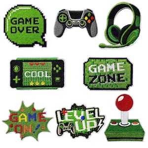 May include: A collection of embroidered gaming patches in various shapes. Designs include a green "Game Over" speech bubble, a gray game controller, a green headset, a handheld game console with "Cool" text, a "Game Zone" patch, a "Game On!" patch, a "Level Up" patch, and a joystick.