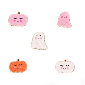 May include: Five felt Halloween patches, two pink pumpkins with smiling faces and two pink ghosts with smiling faces, and one orange pumpkin with a smiling face.